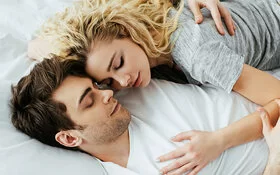 Ein glückliches junges Paar liegt auf dem Bett und umarmt sich.