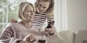 Seniorin und Angehörige schauen auf ihre Smartphones