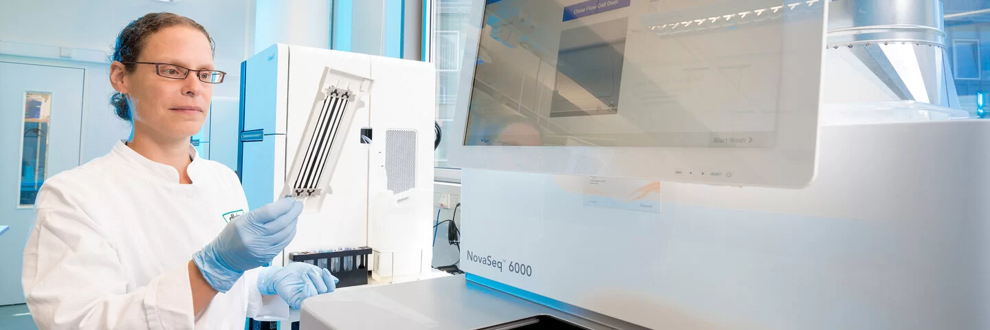 Eine Frau im weißen Kittel steht an einer Sequenzer Serviceeinheit zur Durchführung von Genomsequenzierungen am Deutschen Krebsforschungszentrum in Heidelberg.