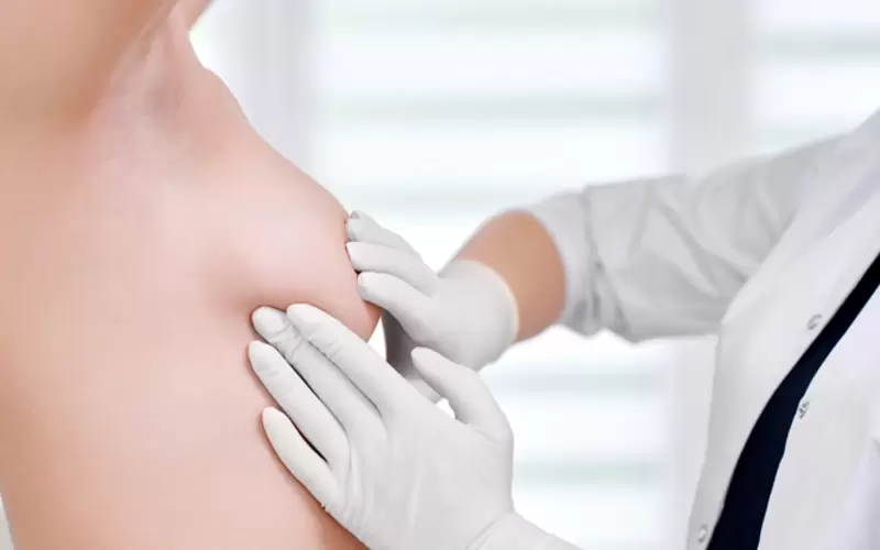 Eine Ärztin tastet die rechte Brust einer jungen Frau ab. 