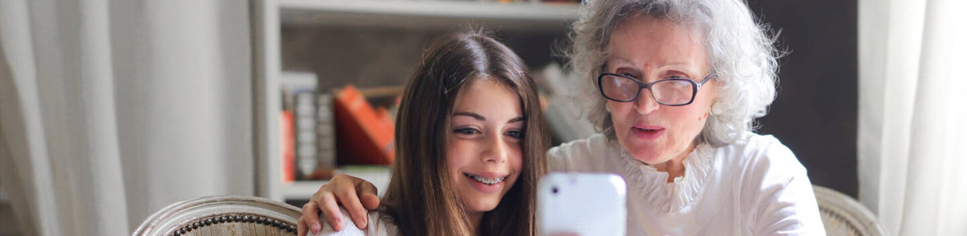 Eine Seniorin und ihre Enkelin schauen auf ein Smartphone.