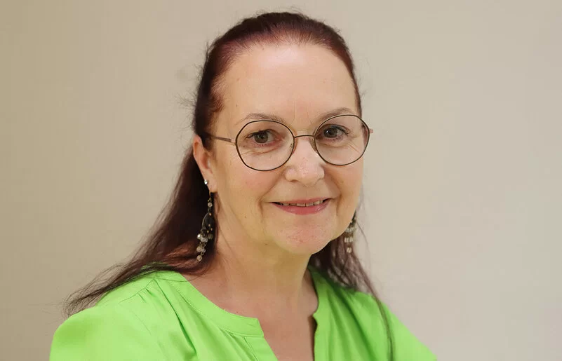 Claudia Missel trägt eine Brille und eine grüne Bluse und lächelt in die Kamera.