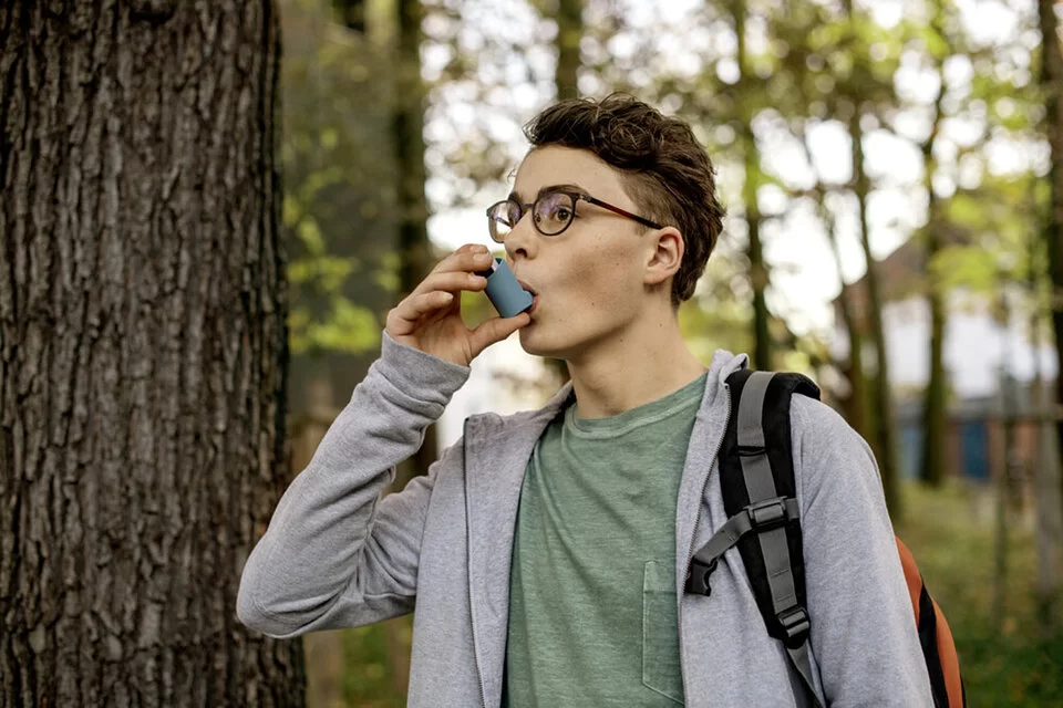 Ein Asthma-Patient ist im Freien und verwendet einen Inhalator. Erfahren Sie mehr über die Krankheit.