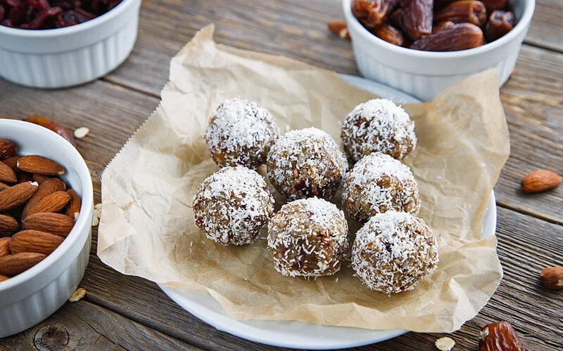 Ein Teller mit Energy Balls aus getrockneten Früchten, Nüssen und Haferflocken mit einem Kokosflockenmantel.