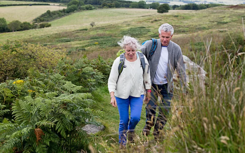 Zwei ältere Menschen gehen wandern, denn Bewegung kann das Risiko einer Darmkrebserkrankung senken.