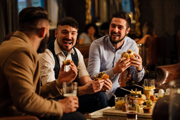 Drei Männer genießen ihr Essen in einem mediterranen Restaurant.