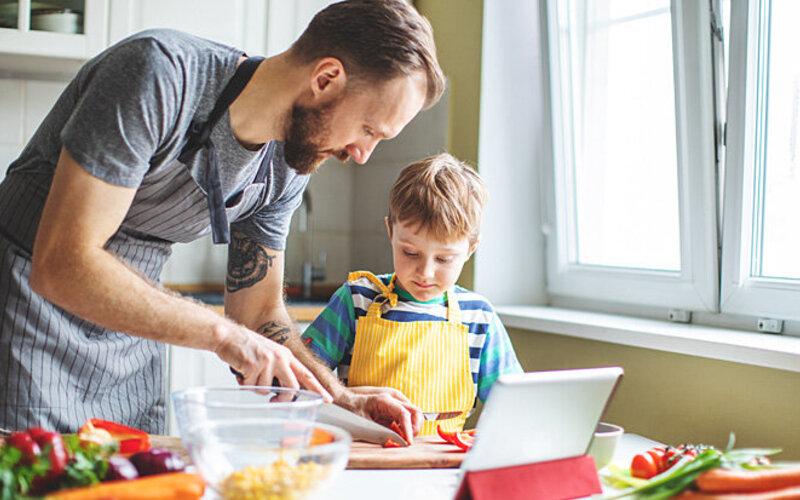 Mann nimmt seiner Frau Mental Load ab und kocht gemeinsam mit dem Sohn das Essen.