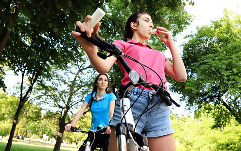 Eine Frau benutzt beim Joggen mit Asthma ihr Asthmaspray.