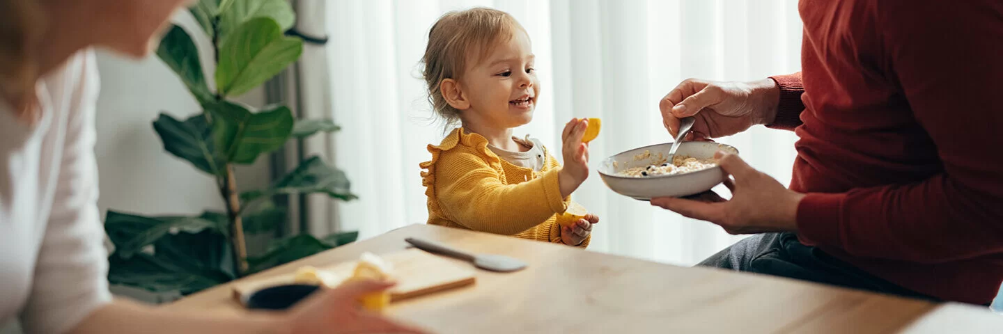 Vater reicht seinem Kleinkind gesundes Essen.