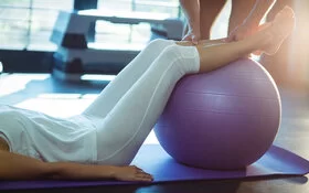 Frau im Fitnessstudio trainiert mit Gymnastikball