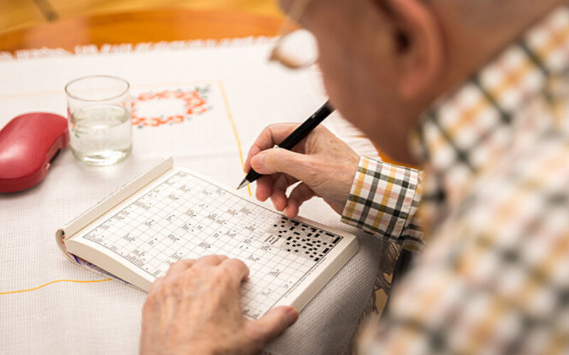 Ein alter Mann löst ein Kreuzworträtsel.