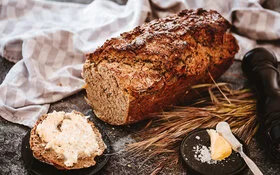 Eine Scheibe frisch gebackenes Dinkelbrot mit Butter bestrichen.