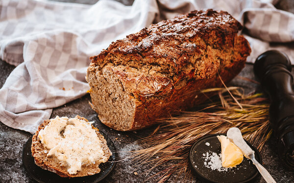 Eine Scheibe frisch gebackenes Dinkelbrot mit Butter bestrichen.