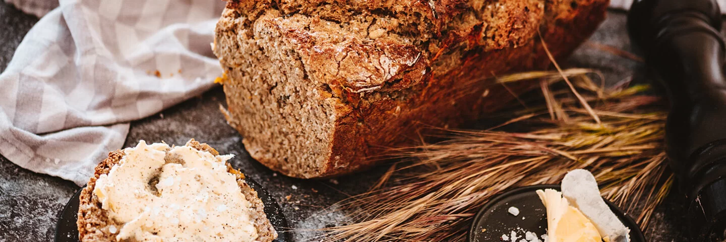 Eine Scheibe frisch gebackenes Dinkelbrot mit Butter bestrichen.