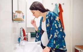Eine junge Frau putzt sich die Zähne, denn in der Schwangerschaft spielt die Zahnreinigung eine wichtige Rolle.