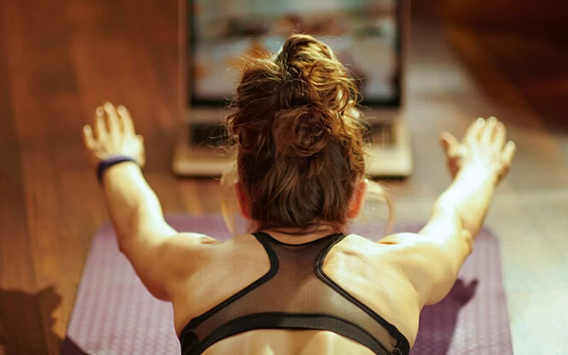 Zum Sport motivieren: Frau macht Sport zu Hause mit Online-Tutorial.  