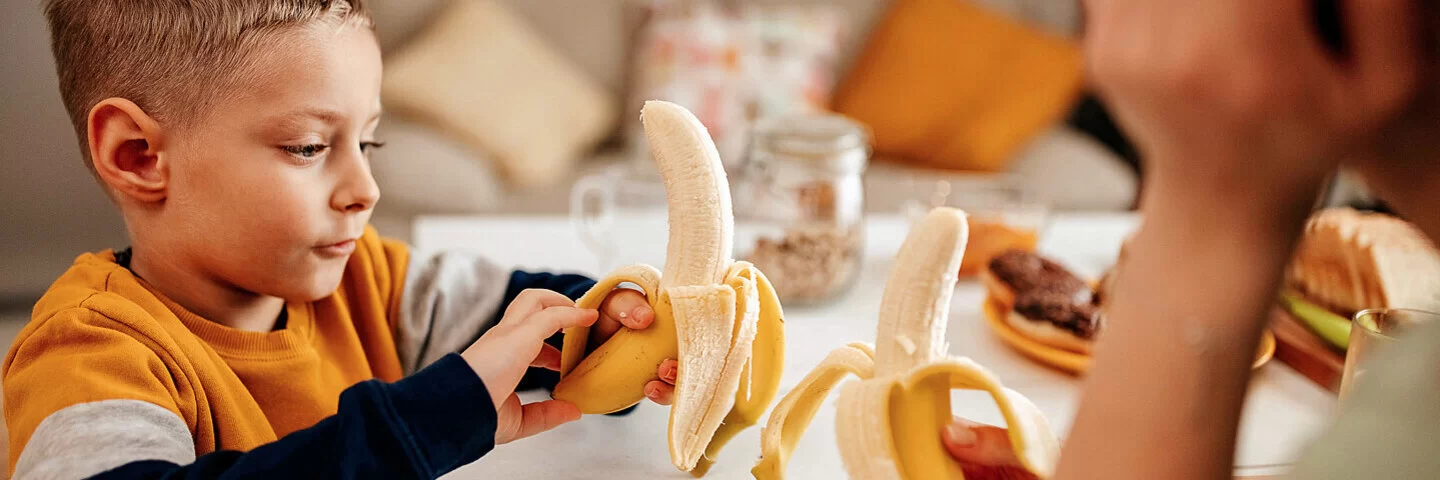 Mutter und Sohn essen gemeinsam Bananen – sie wissen, wie gesund das Obst ist.