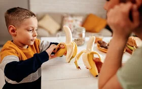 Mutter und Sohn essen gemeinsam Bananen – sie wissen, wie gesund das Obst ist.