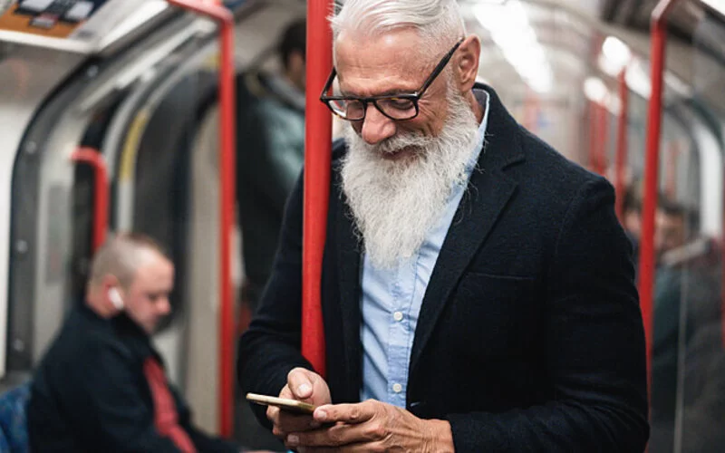 Ein Mann mit Bart und Smartphone fährt mit der U-Bahn als nachhaltiges Verkehrsmittel zur Arbeit.