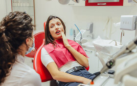Eine junge Frau hat Zahnschmerzen durch ihre Weisheitszähne und ist beim Zahnarzt.