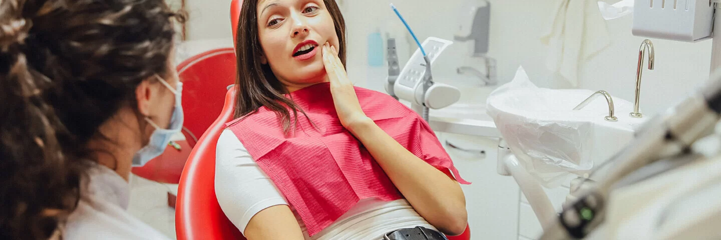 Eine junge Frau hat Zahnschmerzen durch ihre Weisheitszähne und ist beim Zahnarzt.
