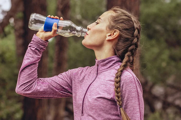 Eine Frau trinkt Wasser aus einer Flasche.