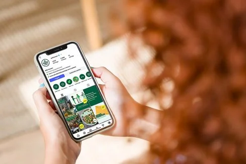 Ein Frau hält ihr Mobiltelefon in den Händen und schaut auf den Bildschirm.