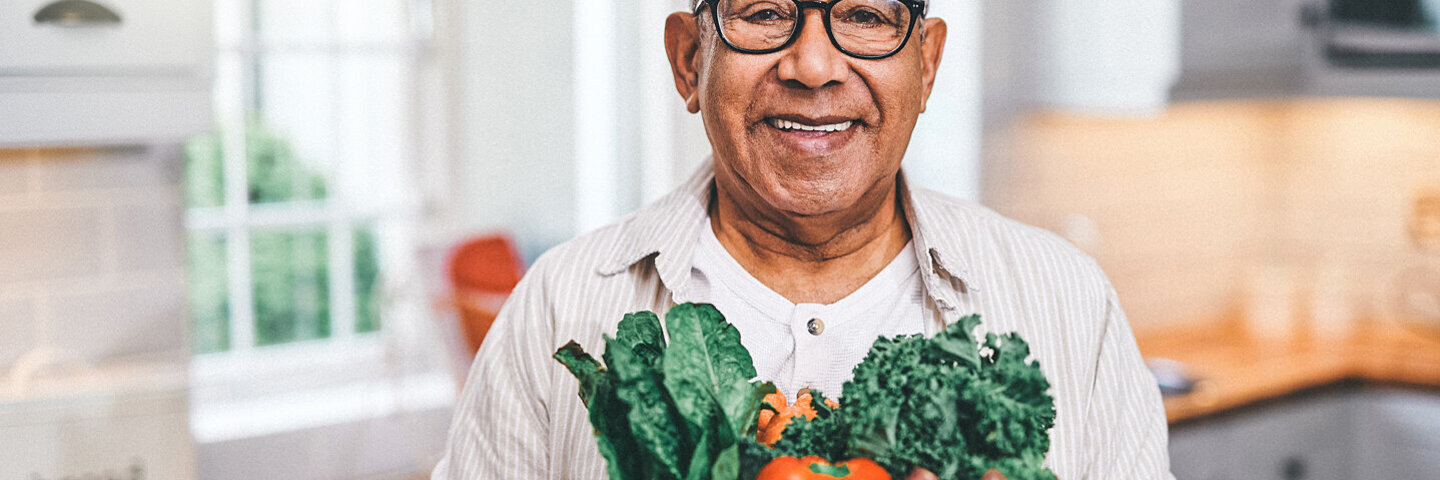 Ein Mann trägt eine Einkaufstüte mit frischem Obst und Gemüse – enthaltene Vitamine stärken das Immunsystem.