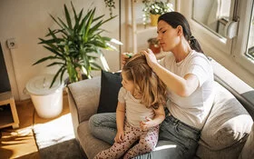 Eine Mutter kämmt die Haare ihrer Tochter mit einem Läusekamm aus.