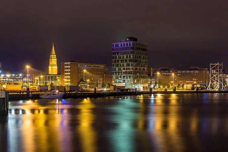 Blick auf den beleuchteten Hafen in Kiel bei Nacht.
