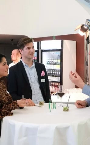 Auf dem Bild kann man drei Personen in der Unterhaltung sehen.