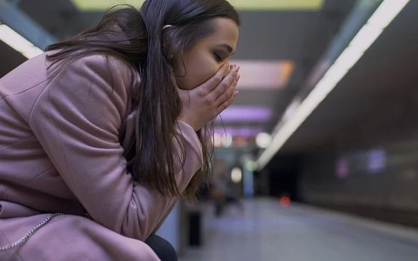 Junge Frau hat eine Panikattacke in einer unterirdischen Bahnstation.