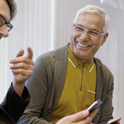 Zwei Männer blicken auf ihre Smartphones. Ihre elektronische Patientenakte können sie mit der App “AOK Mein Leben” aufrufen.