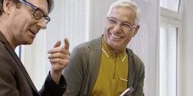 Zwei Männer blicken auf ihre Smartphones. Ihre elektronische Patientenakte können sie mit der App “AOK Mein Leben” aufrufen.