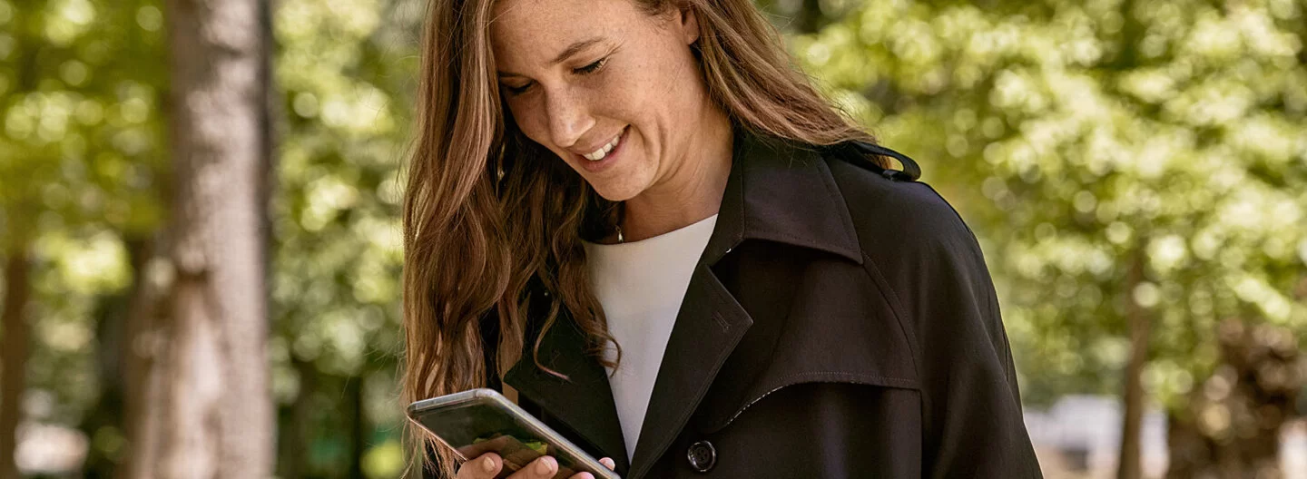 Eine junge Frau liest Nachrichten auf dem Smartphone. Mit dem AOK-Newsletter ist sie bestens informiert.