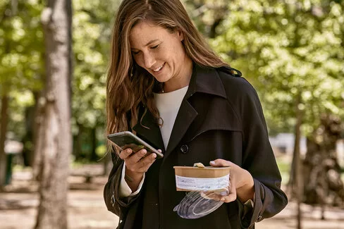 Eine junge Frau liest Nachrichten auf dem Smartphone. Mit dem AOK-Newsletter ist sie bestens informiert.