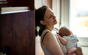 Vom Babyblues betroffene Mutter trägt ihr Baby im Arm.