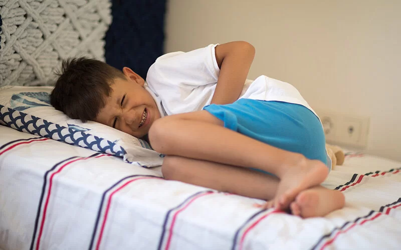 Ein Junge hält sich den Bauch vor Schmerzen – vielleicht hat er eine Blinddarmentzündung.