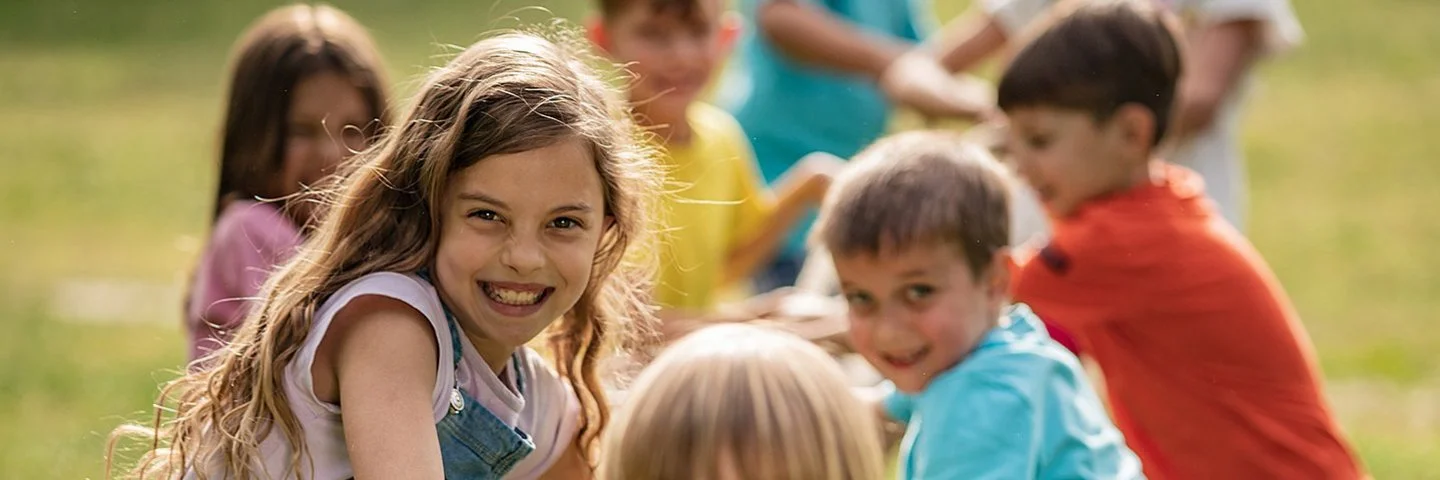 Eine Grundschulklasse spielt im Freien Tauziehen und hat dabei Spaß.