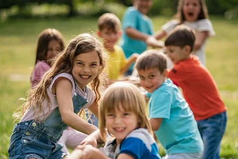 Eine Grundschulklasse spielt im Freien Tauziehen und hat dabei Spaß.