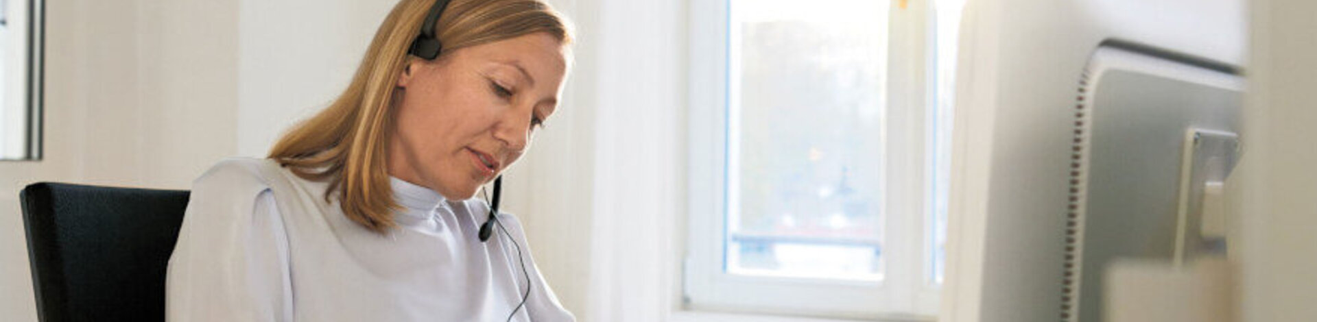 Eine Frau im Büro mit Headset gibt eine telefonische Beratung.
