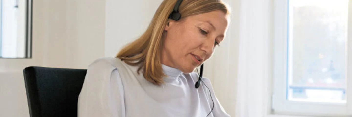 Eine Frau im Büro mit Headset gibt eine telefonische Beratung.