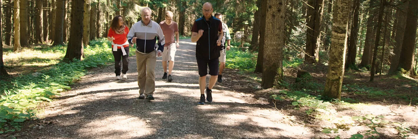 Eine Gruppe älterer Menschen läuft durch einen Wald.