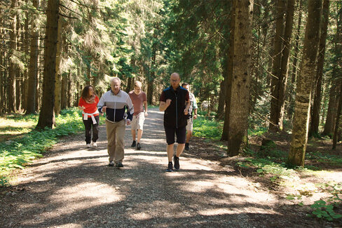 Eine Gruppe älterer Menschen läuft durch einen Wald.
