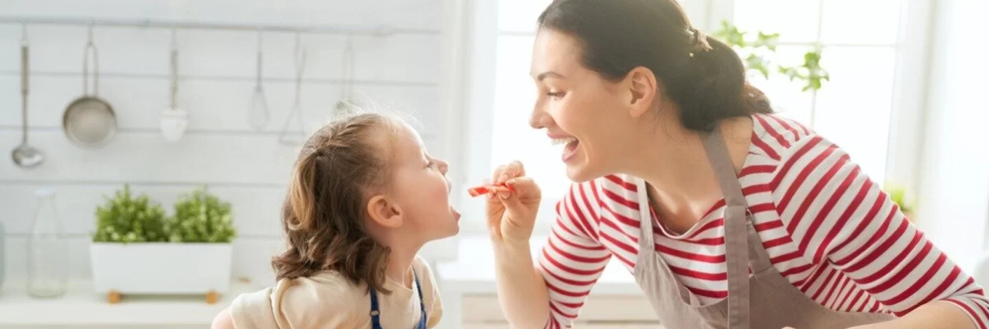 Gesunde Ernährung: Eine Mutter hält ein Stück Tomate in der Hand und gibt sie ihrem Kind.