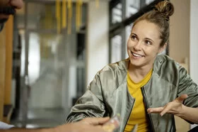 Eine junge Frau blickt nach rechts und lacht. Die AOK unterstützt mit dem Gesundheitsnavigator bei der Suchen nach geeigneten Ärzten.