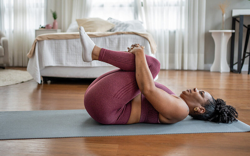 Eine Frau dehnt sich auf ihrer Yogamatte.