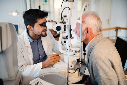 Augenarzt führt eine Augenuntersuchung mit einem Spaltlampengerät bei einem älteren Mann durch.