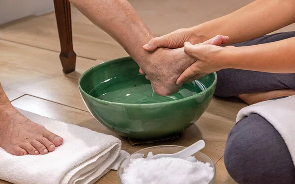 Eine Pflegekraft macht einer Patientin mit diabetischem Fuß ein Fußbad.
