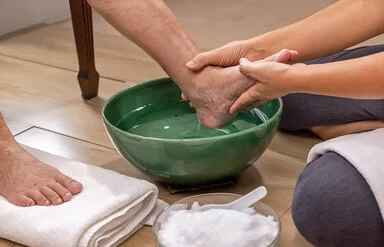 Eine Pflegekraft macht einer Patientin mit diabetischem Fuß ein Fußbad.